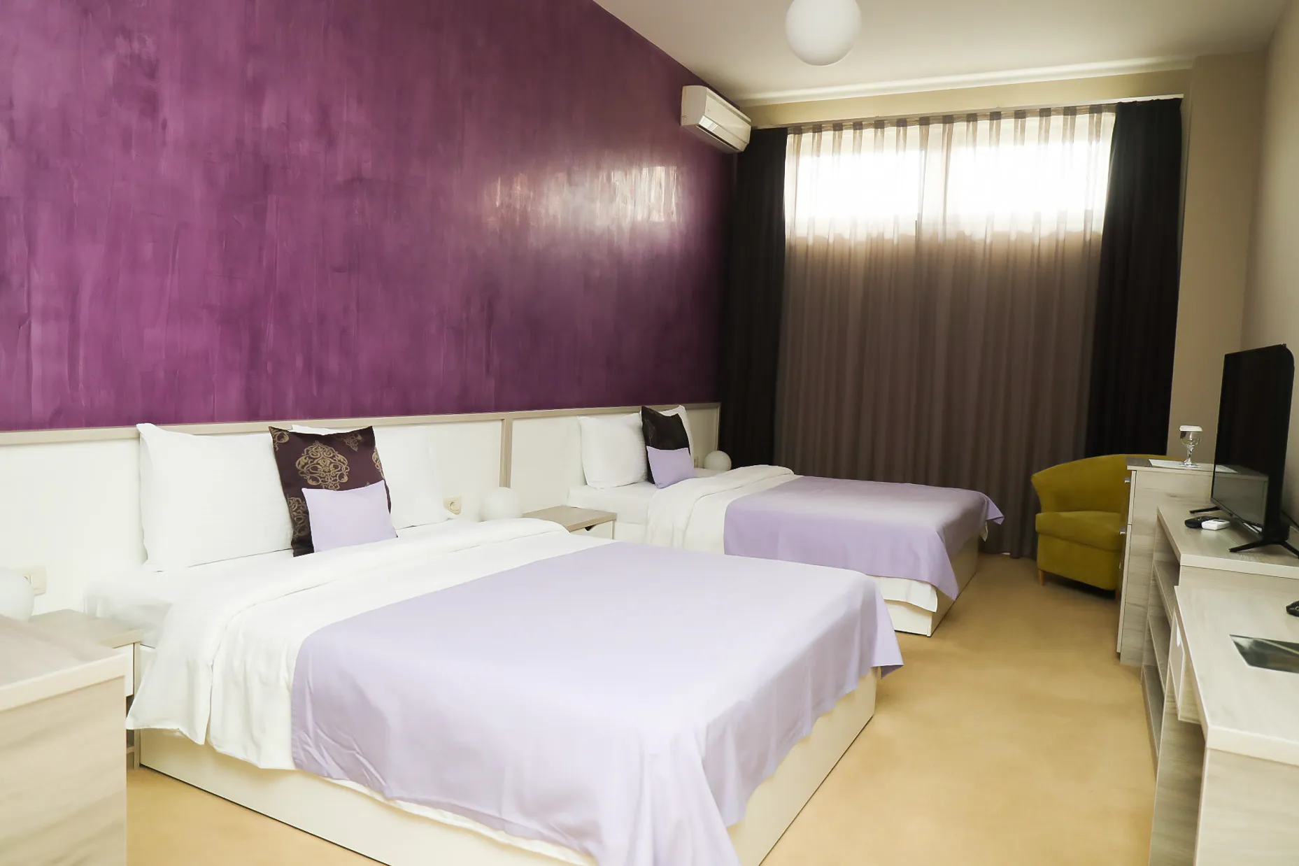 The Deluxe Family Room at Coconut, with three beds against a plum-coloured wall