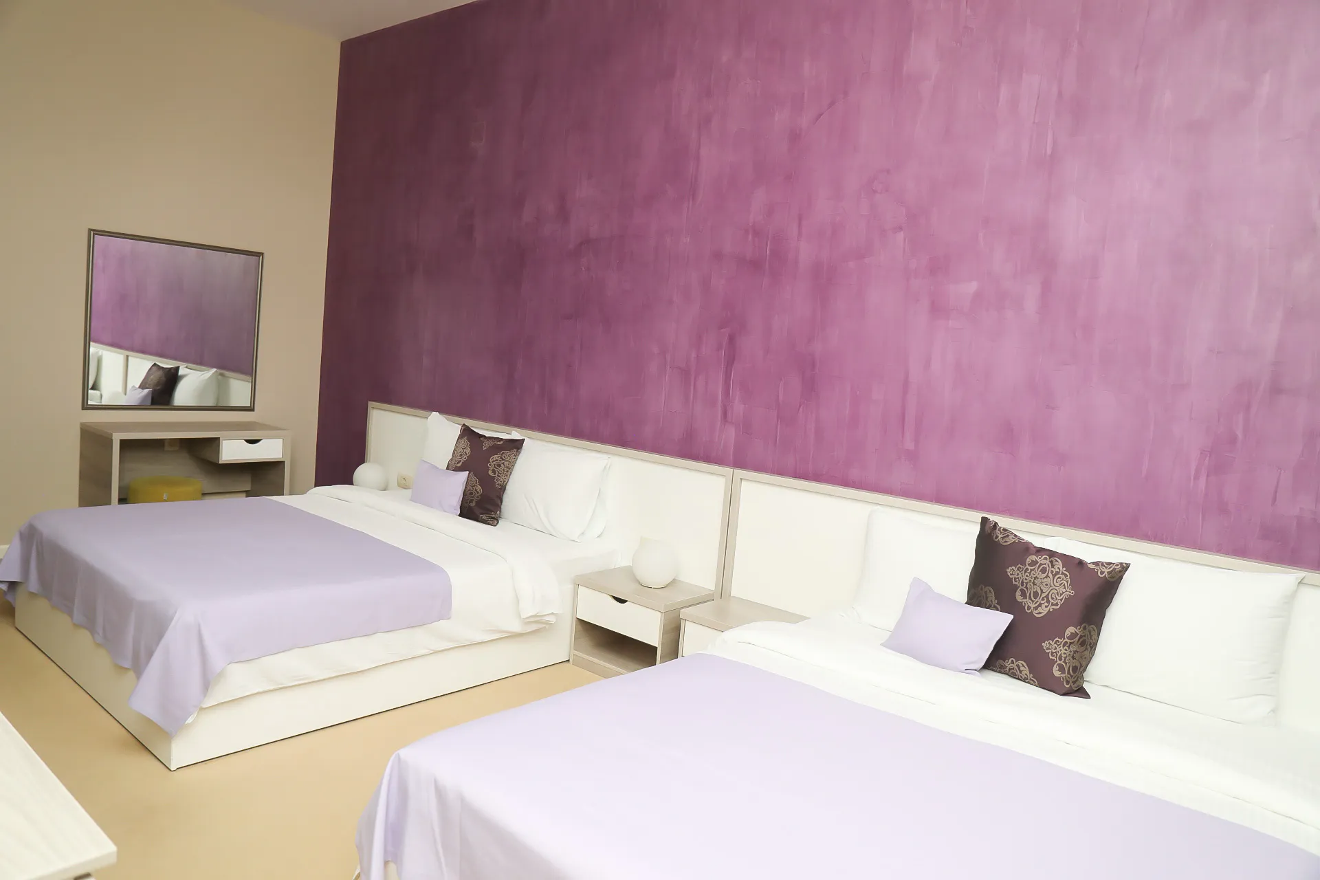 The Deluxe Family Room at Coconut, with three beds against a plum-coloured wall
