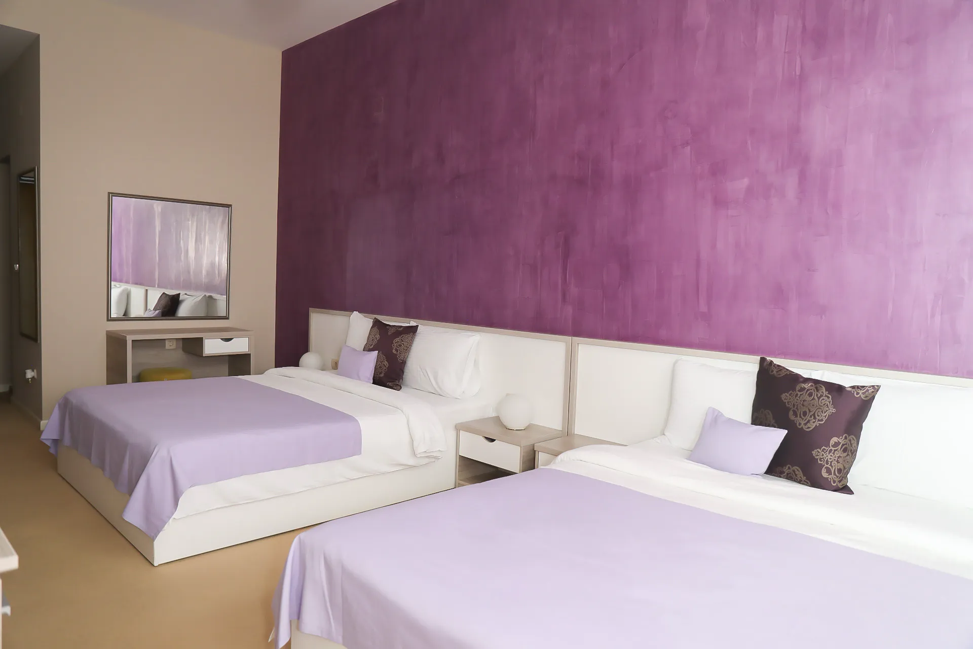 The Deluxe Family Room at Coconut, with three beds against a plum-coloured wall
